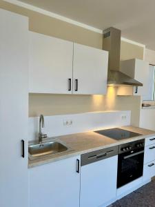 a kitchen with white cabinets and a sink at Appartements Rocky Lake in Techelsberg am Worthersee +12 photos