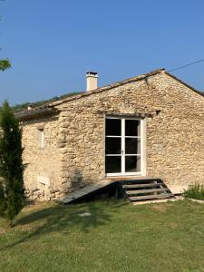a stone house with a window and stairs in a yard at Mas du 18e siècle au calme entouré de champs de lavandes in Pierrerue +15 photos