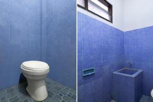 a bathroom with a toilet and a blue tiled wall at OYO 94704 Geria Ratu Prahandari in Kerobokan