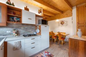 a kitchen with white cabinets and a dining room at La Casa dei Cervi a Vinigo in Vodo Cadore