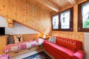 a log cabin bedroom with a red couch and windows at La Casa dei Cervi a Vinigo in Vodo Cadore
