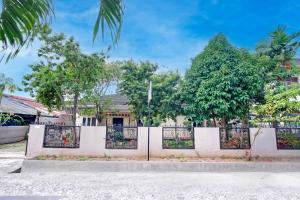 a white fence with trees in front of a house at Hotel O Twin Kostel in Palembang