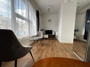a living room with two chairs and a television at Cosy Flat Goodmayes in Goodmayes