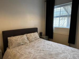 a bed in a bedroom with a large window at Cosy Flat Goodmayes in Goodmayes