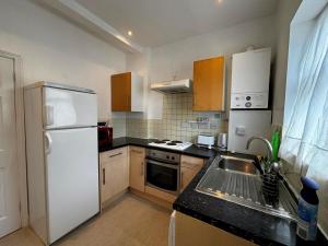 a kitchen with a white refrigerator and a sink at Cosy Flat Goodmayes in Goodmayes