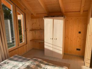 Un dormitorio de una cabaña de madera con una cama y una ventana. en Ferienhaus Remise, en Seehausen am Staffelsee