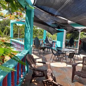 a patio with chairs and tables and a blue building at La maison des couleurs in Sabaneta de Yásica +7 photos