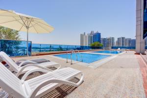a swimming pool with two chairs and an umbrella at Majestic Tower in Dubai