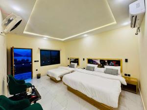 a hotel room with three beds and a window at North Fields Resorts in Skardu