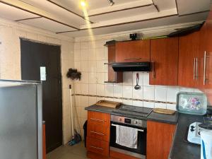 a kitchen with wooden cabinets and a stove top oven at Konayethu BnB in Mdantsane