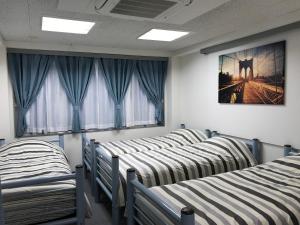 a row of beds in a room with windows at TOKYOtomo in Wada