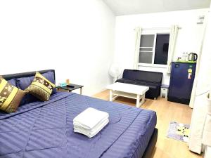 a bedroom with a purple bed and a living room at Cina Home in Chiang Mai