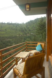 a porch with a table and a bench on a balcony at Khaapus Home Naggar in Kāndi