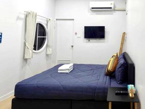 a bedroom with a blue bed and a tv at Cina Home in Chiang Mai