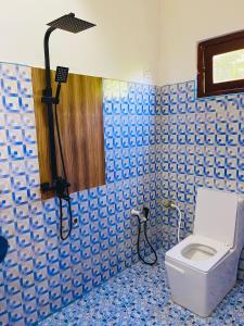 baño con aseo en una pared de azulejos azules en Tissa Yala Lake View Hotel, en Tissamaharama