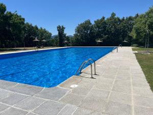 a large swimming pool with blue water at Casa Mama Puchi in Cercedilla