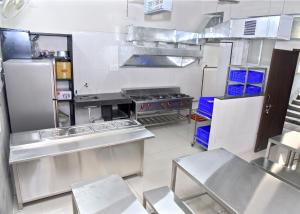 a large commercial kitchen with a stove and refrigerator at Dwarka Yatri Niwas in Kolhapur