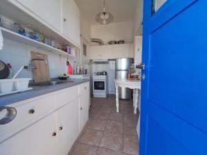 a kitchen with white cabinets and a blue door at Aias View in Panayía