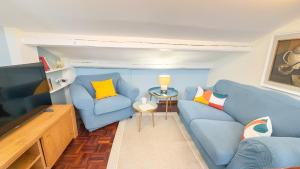 a living room with two blue chairs and a flat screen tv at Dimora Sotto le Stelle by Ca-Sa Check in Chioggia