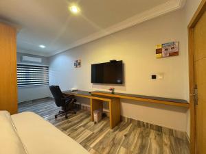 a room with a desk with a tv on a wall at Bayview in Accra