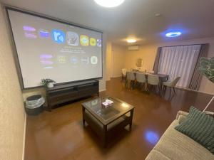 a living room with a large screen television and a table at ReStayしっぽタウンヴィラ今宮駅 in Osaka