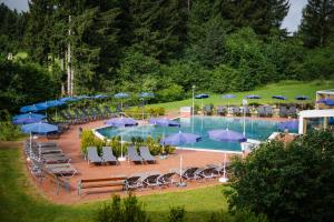 a swimming pool with blue umbrellas and chairs and tables at Vivea Hotel Bad Traunstein 