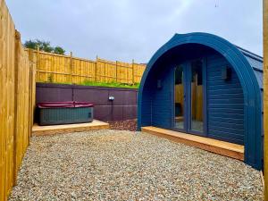 a blue shed sitting next to a wooden fence at 60 Mile Inn - Luxury Pods with Hot Tubs in Bridge of Orchy