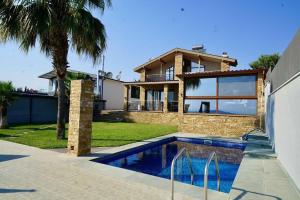 a house with a swimming pool in front of a house at Anesi Beachfront Luxury Villa in Nea Moudania