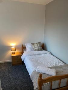 a bedroom with a bed and a night stand with a lamp at Spacious Luxurious Serviced Accommodation 3 in Warmsworth