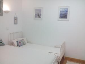 シントラにあるCasa da Camélia - Sintraの白い部屋のベッド2台 壁に絵画が飾られています。