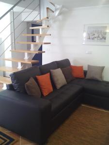 um sofá preto numa sala de estar com uma escada em Casa da Camélia - Sintra em Sintra