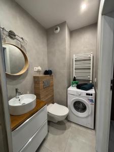a bathroom with a toilet sink and a washing machine at Urocza i nowoczesna kawalerka - Łódź w pobliżu centrum in Łódź