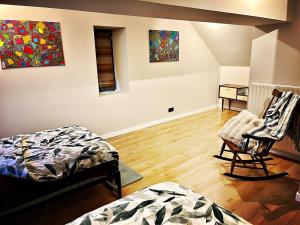 a room with two beds and a chair and paintings at De Zweverik in Dessel