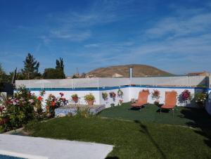 ein Garten mit zwei Stühlen und einer Mauer mit einem Hügel im Hintergrund in der Unterkunft Parada del Herrero casa rural in Zújar