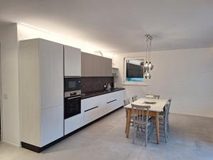 a kitchen with white cabinets and a table with chairs at Riflessi sul lago in Baselga di Pinè