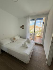 Un dormitorio blanco con una cama y un balcón. en Lovisi Suite Playa del Cura - OCEAN & POOL VIEW, en Mogán 18 fotos más