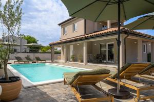 a house with a swimming pool with chairs and an umbrella at Villa Casa della Capra by Istrialux in Foli