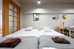 two beds with towels on them in a bedroom at Near Shibuya Station 4Beds 5Max A175 in Tokyo