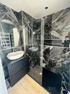 a bathroom with two sinks and black marble walls at RIVIERA - 2 Pièces de Charme - Vue Lac - Clim - Parking in Annecy