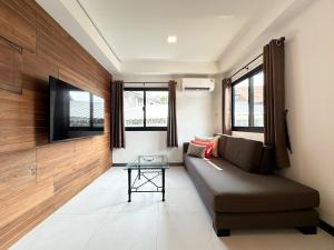 a living room with a couch and a flat screen tv at Freeda House Bang Tao Beach - Near Muay Thai Gym in Ban Lum Fuang