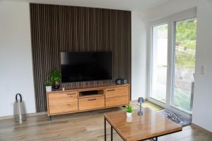 a living room with a flat screen tv on a wooden entertainment center at Ferienwohnung Passhöhe - Familienurlaub- Wanderurlaub Schwarzwald - Hunde willkommen- Hochschwarzwaldcard - Haus Wiesenquelle in Feldberg