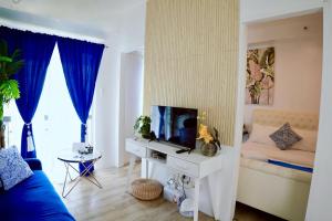 Santorini Lia Soleil at La Bella Tagaytay في Galicias: غرفة معيشة مع أريكة زرقاء وتلفزيون