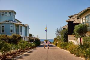 dos personas caminando por una calle frente a las casas en Pointe Us to the Beach by 30A Escapes, en Rosemary Beach