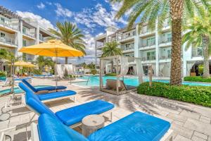 un complejo con piscina, sillas azules y sombrilla en Pointe Us to the Beach by 30A Escapes, en Rosemary Beach