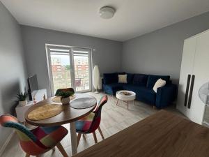 a living room with a table and a blue couch at Urocza i nowoczesna kawalerka - Łódź w pobliżu centrum in Łódź