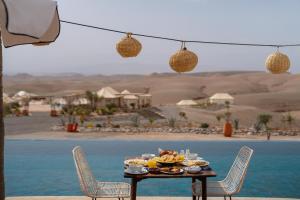 a table with food on it next to a body of water at Mia Agafay Resort in El Karia