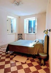 a bedroom with a bed and a chair and two windows at La Gatta in Montemerano