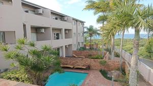 an apartment building with a swimming pool and palm trees at Sunrise Beach Resort in Amanzimtoti