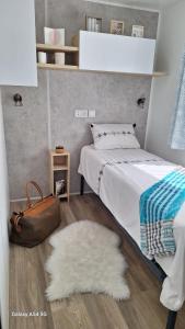 a bedroom with a bed and a brown purse and a rug at Charmant mobil home camping Les Embruns in Lège-Cap-Ferret