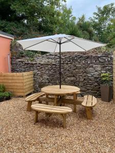 mesa de picnic con sombrilla y 2 bancos en The Colony Townhouse Dingle, en Dingle